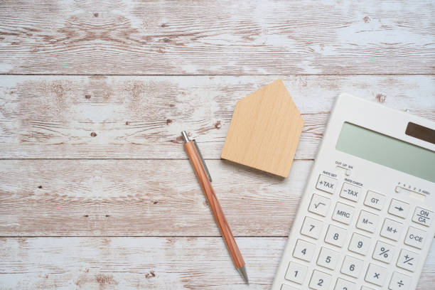 una calculadora blanca, un bolígrafo y un manual de la casa. - tarifa fotografías e imágenes de stock