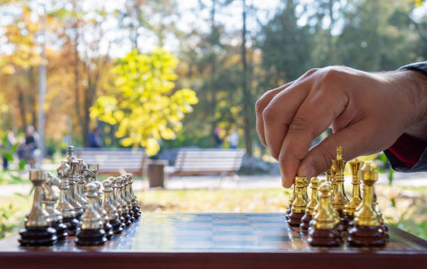 istock Outdoor chess game. Chessboard with figures, close-up, hand makes the first move. Selective focus. 1352215194