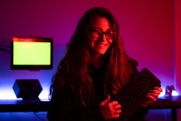 istock Smiling young woman holding keyboard in front of her computer desk 1352215568