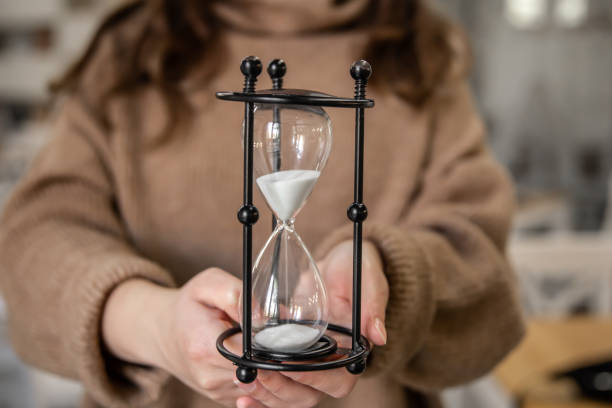 sablier en verre vintage en gros plan dans les mains des femmes. - sand clock human hand hourglass photos et images de collection