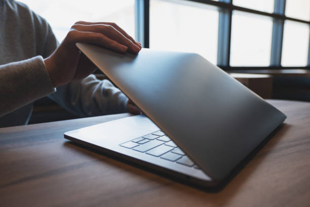 hands close and open a laptop computer on table after finished using it - in en uitschakelen stockfoto's en -beelden