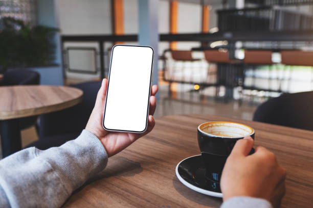 istock A woman holding mobile phone with blank desktop screen while drinking coffee 1352218638
