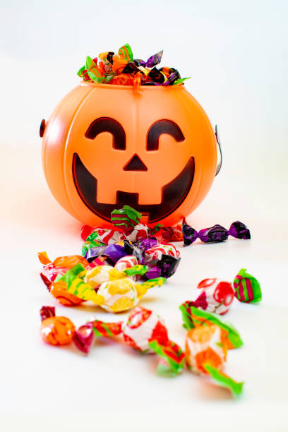 istock Halloween pumpkin with candies by the side, with white background. 1352220204