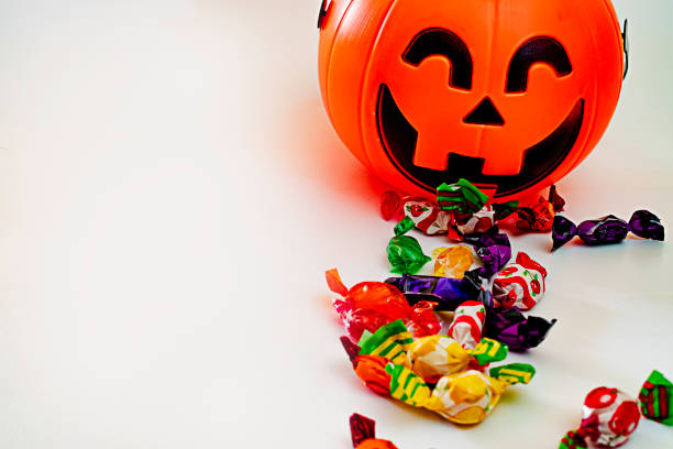 istock Halloween pumpkin with candies by the side, with white background. 1352220242