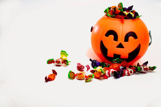 istock Halloween pumpkin with candies by the side, with white background. 1352220287