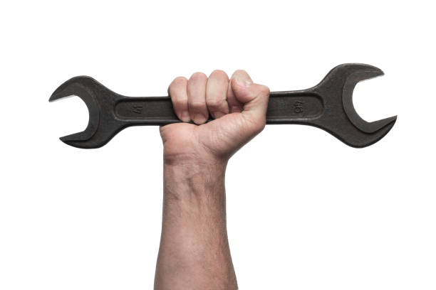 istock Male worker's hand holds a large wrench isolated on white 1352220342