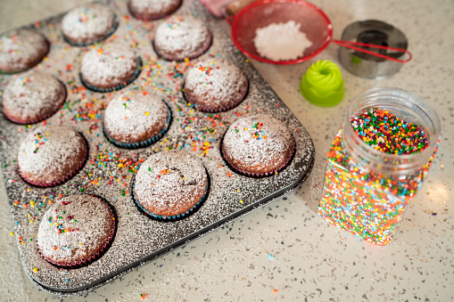 Above shot of  freshly baked muffins in a tray. Close-up of homemade tasty  muffins, decorated with powder sugar and funny sprinkles on top