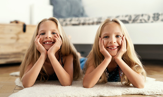 Two girls and boy in light clothes are sitting on white background in studio. Baby tooth. Happy childhood. Preschool age. Cheerful children. Playful girl. Middle eastern boy