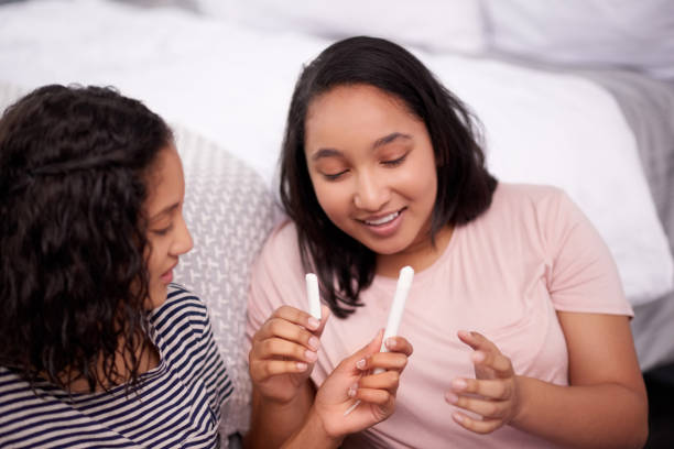 Cropped shot of two teenage girls talking about menstruation at home stock photo