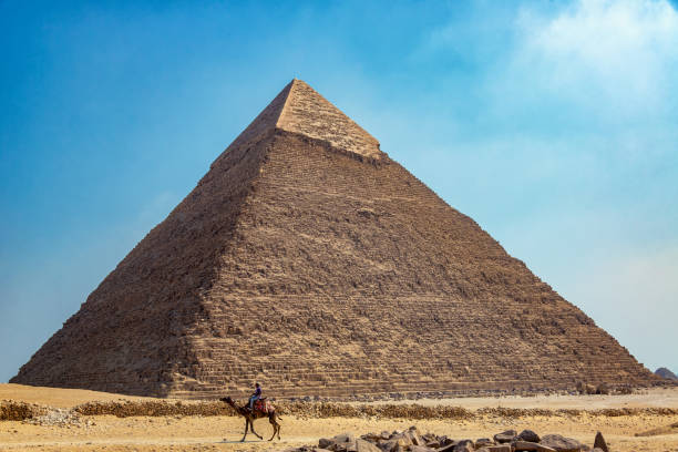 Camel and Rider at the Giza Pyramid Complex Giza, Egypt - July  14, 2021: A person rides a camel near the Great Pyramid in Giza, Egypt kheops pyramid stock pictures, royalty-free photos & images