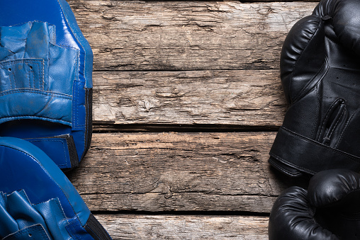 Boxing gloves on the old wooden table flat lay background with copy space.