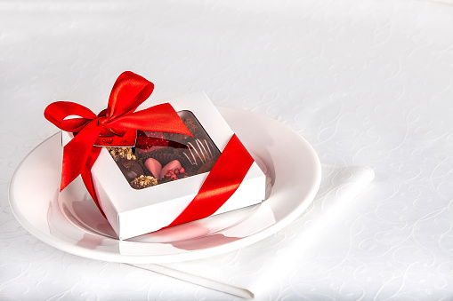 gift box with chocolate candies on the plate over white background, copy space. valentine s day