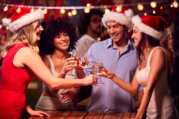 Multi-Cultural Group Of Friends Celebrating Making Toast Enjoying Christmas Party Night In Bar Multi-Cultural Group Of Friends Celebrating Making Toast Enjoying Christmas Party Night In Bar office parties stock pictures, royalty-free photos & images