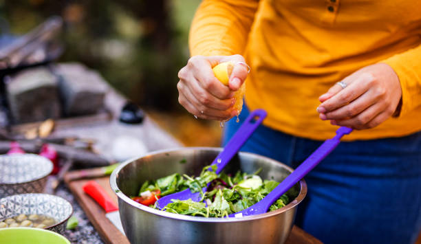 istock Woman`s hands squeeze lemon in healthy salad 1352226617
