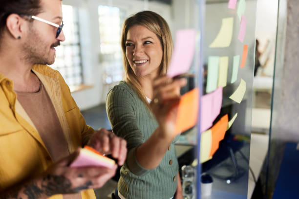 istock Happy creative colleagues making mind map on a glass wall in the office. 1352227581