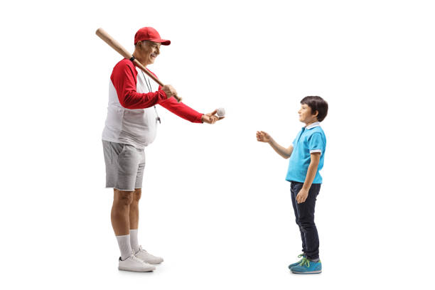 foto de perfil de cuerpo entero de un hombre maduro con un bate de béisbol dándole una pelota a un niño - men baseball baseball cap baseball bat fotografías e imágenes de stock