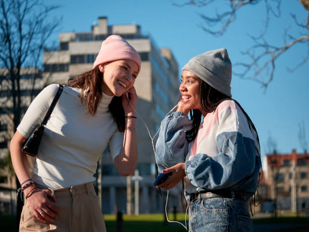 istock Two young girls outdoors using a smart phone with earphones 1352230044