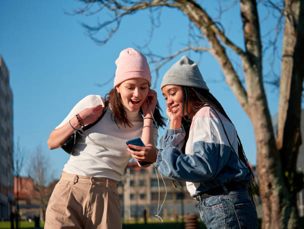 istock Two young girls outdoors using a smart phone with earphones 1352230059