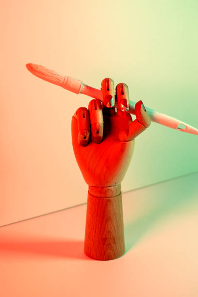 istock Wooden hand with a white paintbrush with red lights 1352231513