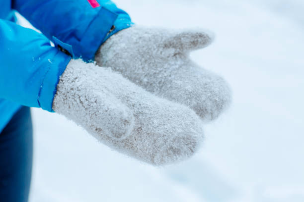 istock Women's hands in light gray knitted mittens with a white snowflakes 1352233676