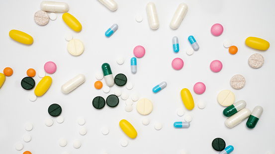 Variety of drugs in capsules and pills of different colors on a white background