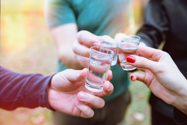 Toast with shot drink outdoors Cropped image of hands toasting with vodka shots. Friends drinking shot alcohol outdoors tequila shot stock pictures, royalty-free photos & images