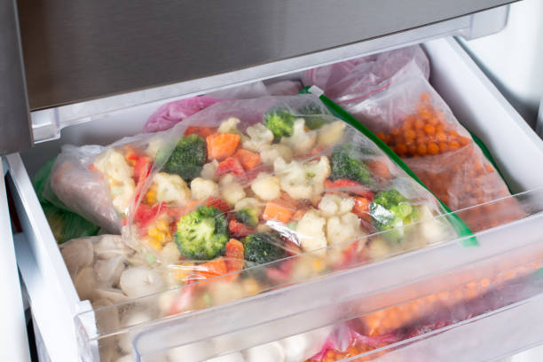 istock Plastic bags with different frozen vegetables in refrigerator. 1352234898