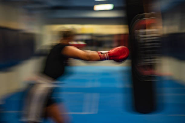 Blurred motion of determined female boxer hitting a punching bag on a sports training in a gum