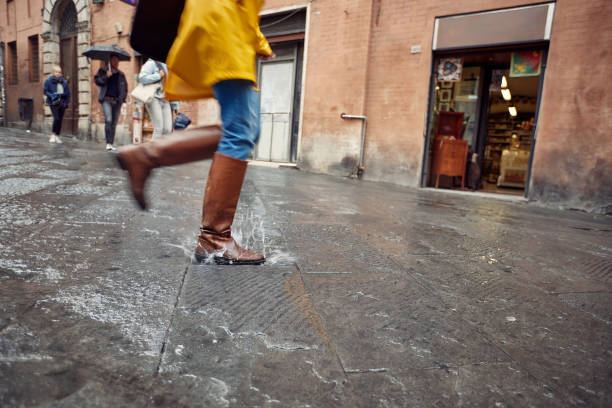 雨の日に水たまりに走ったり飛び乗ったりする。屋外で雨の日。 - umbrella women storm yellow ストックフォトと画像