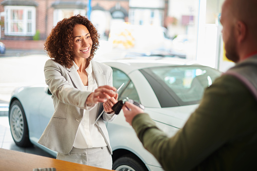 car sales person shanding over car