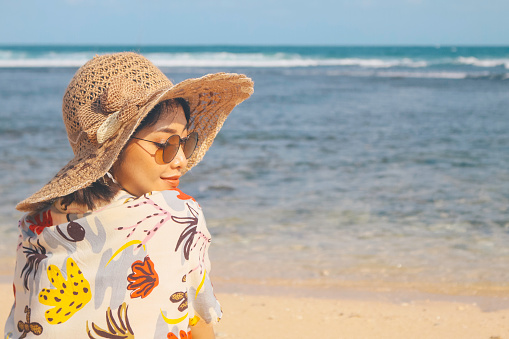 Portrait of happy smiling Asian woman on the beach wear hat