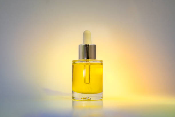 Yellow face oil in yellow spotlight Yellow face oil in glass bottle with dropper on white background with yellow spotlight argon stock pictures, royalty-free photos & images