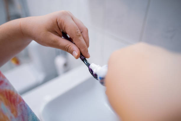istock hands of a tween girl putting toothpaste on toothbrush in bathroom 1352243070