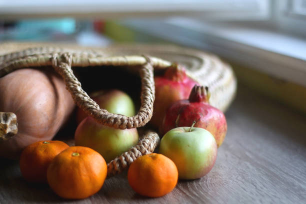 Straw tote bag filled with butternut squash and various fruit. Selective focus.