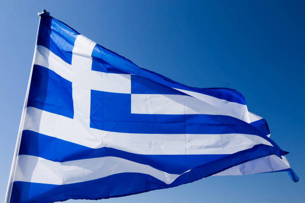 istock Greek flag waving under blue sky 1352244944