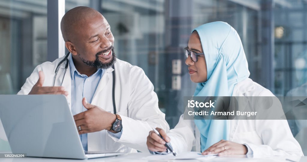 Shot of two medical professionals going through paperwork while using a laptop in an office at work A true mentor will always be by your side Mentorship Stock Photo