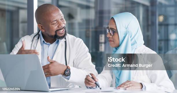 Shot Of Two Medical Professionals Going Through Paperwork While Using A Laptop In An Office At Work Stock Photo - Download Image Now