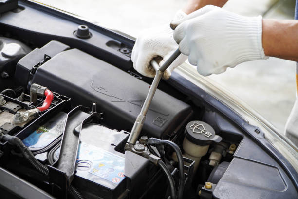 istock Asian mechanic puts the battery in place to work with the car's electrical system using a spanner. 1352246525