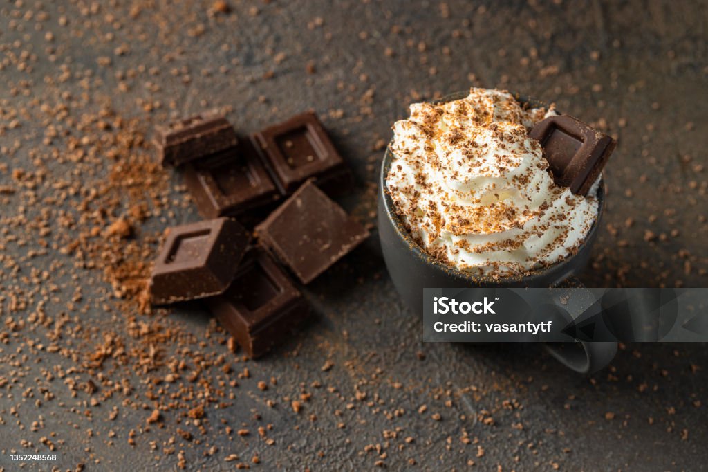 Hot chocolate  cup with whipped cream  and chocolate slices  on dark concrete background. Warm cozy beverage for cold days Mocha Stock Photo