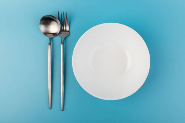 istock Empty plate with fork and spoon on blue background. Flat lay Dishes for breakfast, lunch or dinner Mock up 1352251537