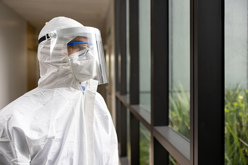 man in mask and protective clothing inside an empty warehouse