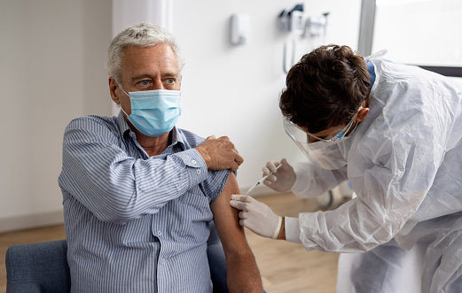 Hombre adulto que recibe una dosis de refuerzo de la vacuna COVID-19 en el hospital photo