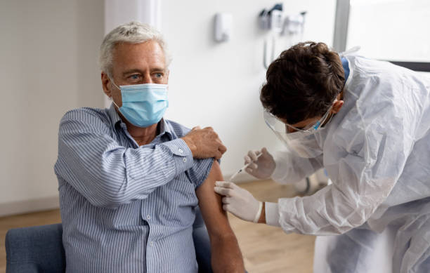 Adult man getting a booster dose of the COVID-19 vaccine at the hospital Latin American adult man getting a booster dose of the COVID-19 vaccine at the hospital - stop the pandemic concepts booster dose photos stock pictures, royalty-free photos & images