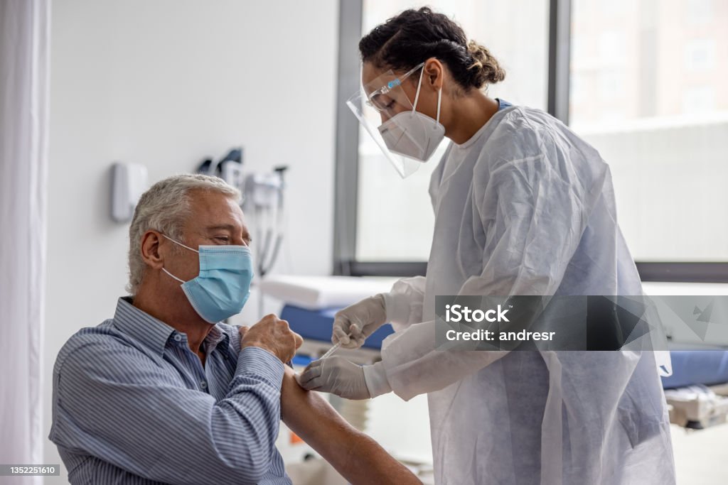 Adult man getting the COVID-19 vaccine at the hospital Adult Latin American man getting the COVID-19 vaccine at the hospital during the pandemic Booster Dose Stock Photo