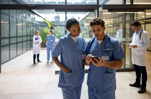 médico en el hospital mostrando algo en su teléfono celular a un compañero de trabajo - hospital entrada fotografías e imágenes de stock
