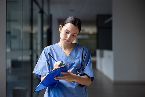 Nurse working at the hospital writing on a clipboard