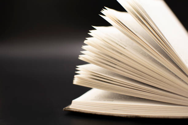 istock an open old book on a black background. The concept of education and development 1352252903