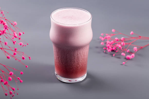 Strawberry latte on grey with flowers behind stock photo