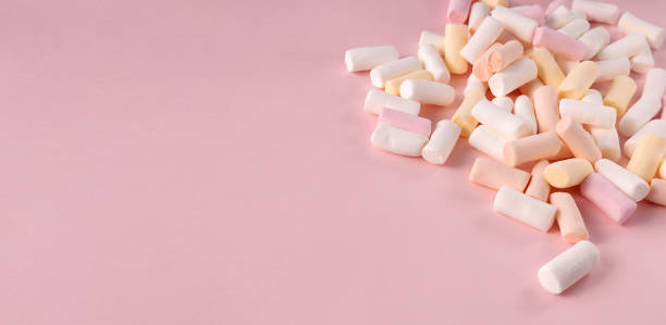 istock Closeup of colored sweet marshmallows on the pink background.Empty space 1352255875