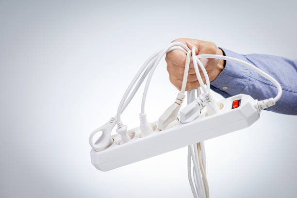 istock Male hand holding overload power board on light grey background with copy space. Save energy concept. Audit electrical equipment. 1352256117